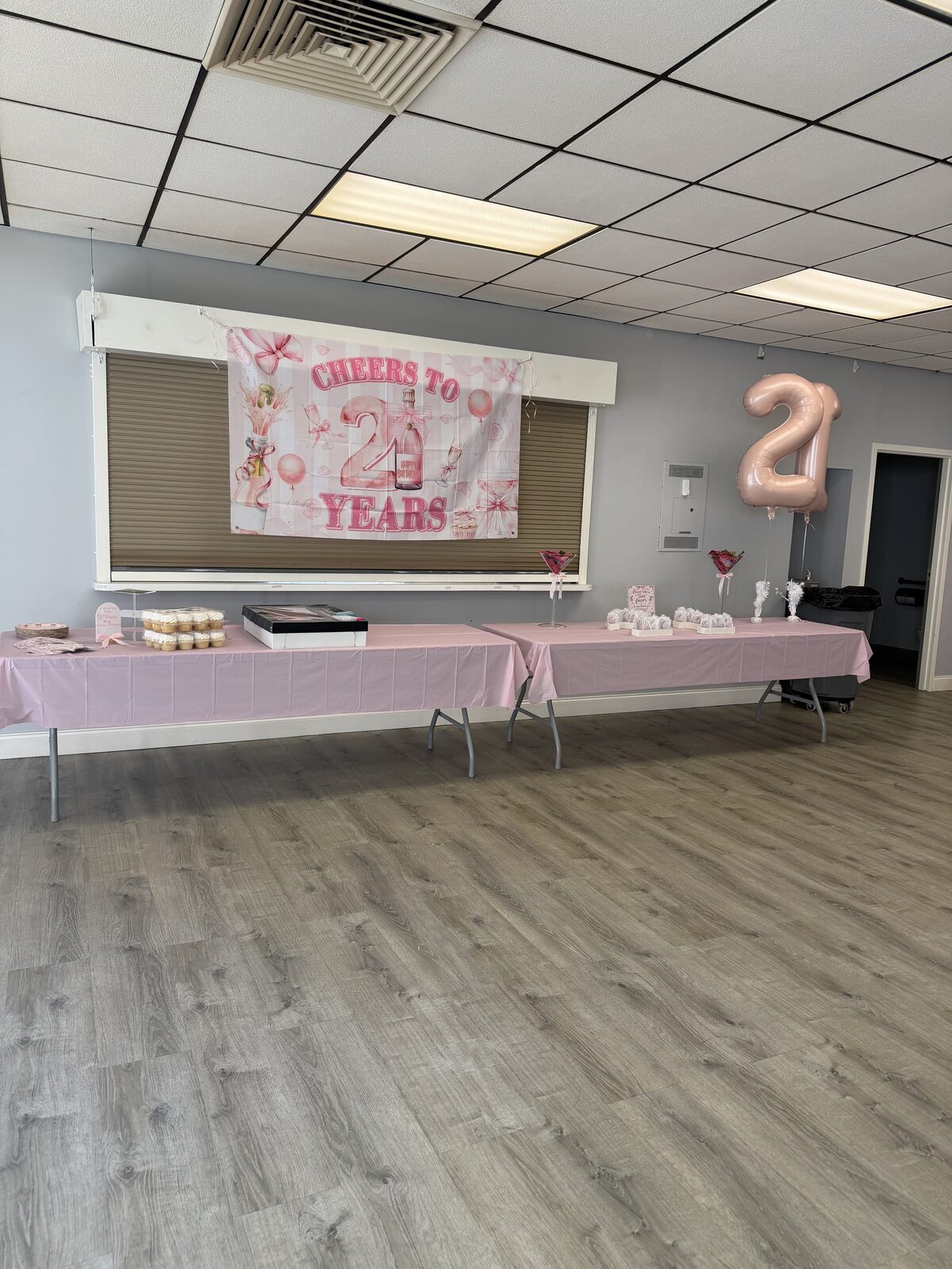 Cheers to 21 Years banner over pink party tables