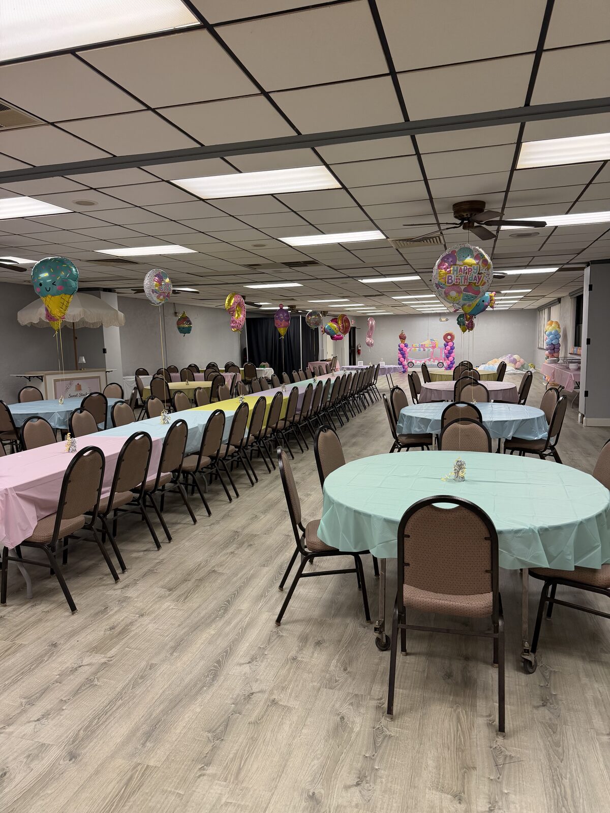 Wide view of the hall with pastel linens and balloons for a birthday