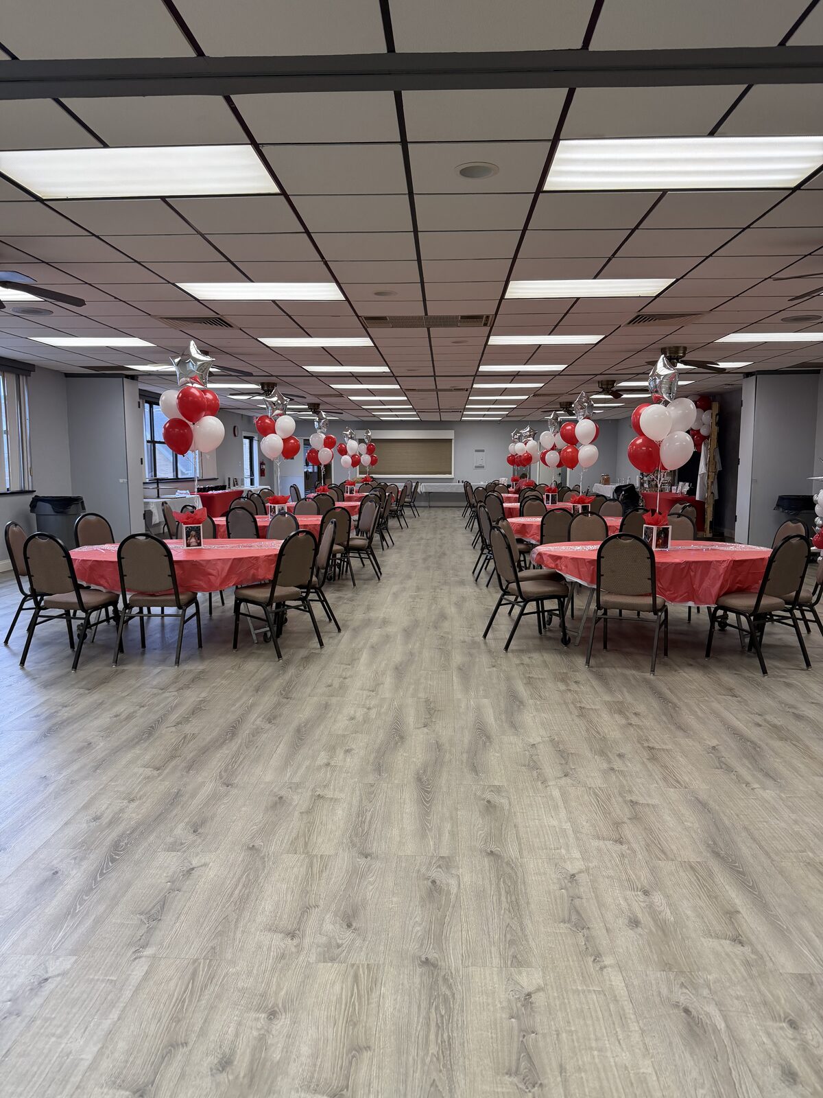 Wide view down the hall with round tables in red linens and balloon centerpieces